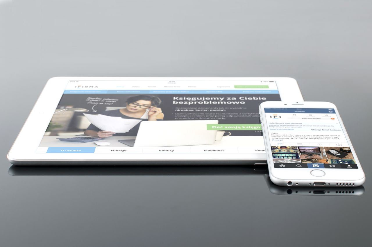 services-03 A contemporary tablet and smartphone showing web content on a reflective surface, emphasizing technology and connectivity.